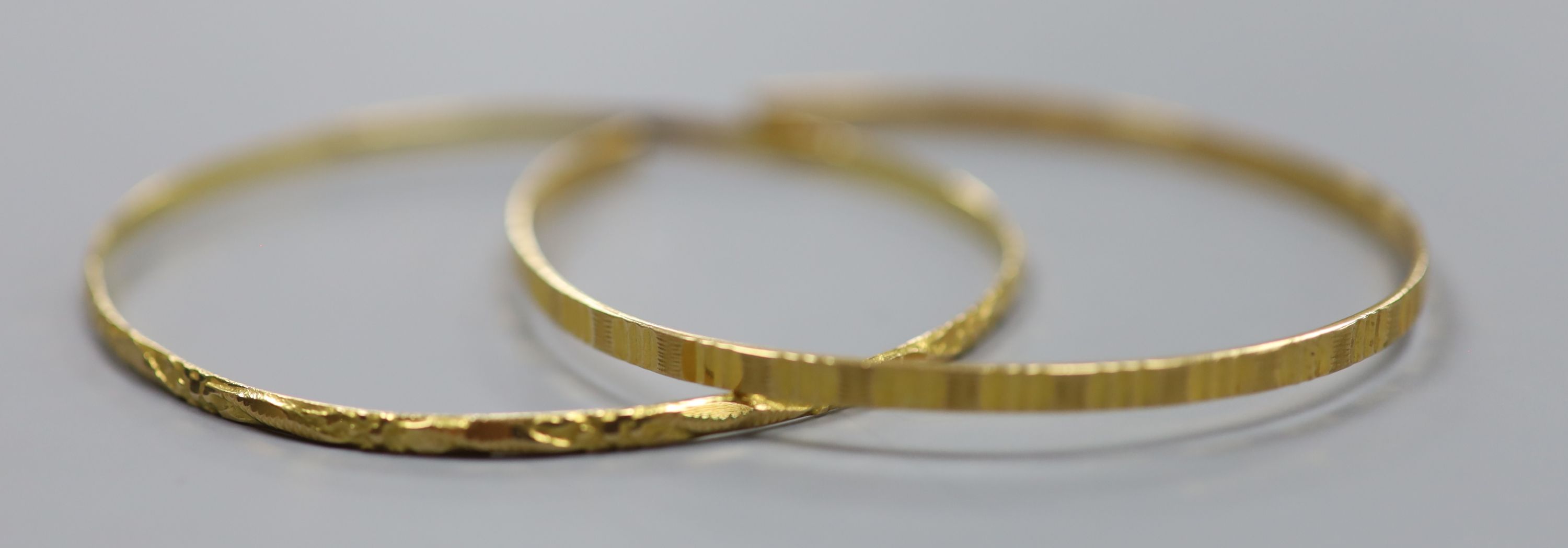 Two Middle Eastern yellow metal bangles (one cut)